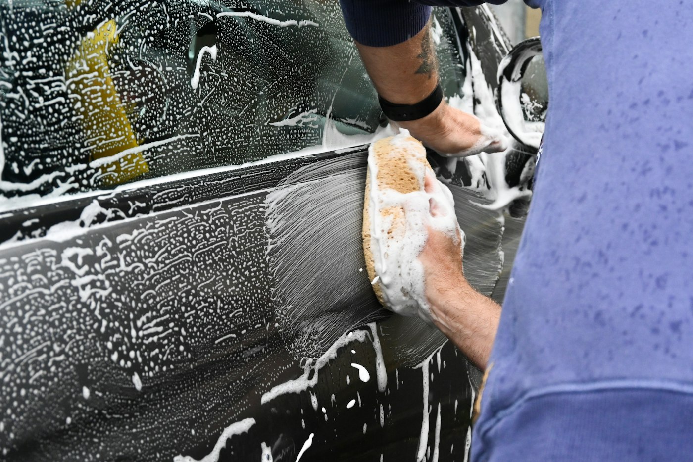 Detailer hand washing a car with a microfiber mitt